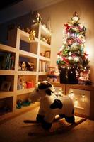 Hobby cow toy against Christmas tree with shining garlands on evening home. photo