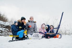 Family plays and sleigh rides in winter outdoor, children having fun, drinking tea. photo