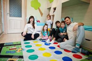 gran familia feliz divirtiéndose juntos, cuatro niños jugando al juego de tornado en casa. foto