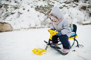 Little girl enjoy a sleigh ride. Child sledding. Kid riding a sledge on winter. photo