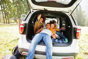 Family at vehicle interior. Father with four kids. Children in trunk. Traveling by car in the mountains, atmosphere concept. photo