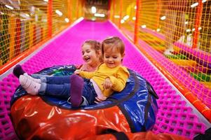 Two sisters sitting in tubing donuts enjoying slides in fun children center. photo