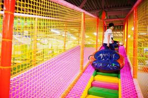 Happy two brothers in tubing donuts enjoying slides in fun children center. photo