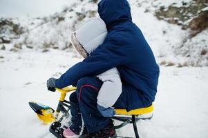 hermano y hermana disfrutan de un paseo en trineo. trineo infantil. niño montando un trineo en invierno. foto