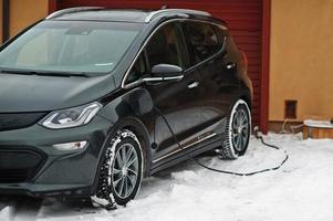 Charging electric car in the yard of house at winter. photo