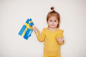 Baby girl in yellow with lemon and Sweden flag, isolated background. photo