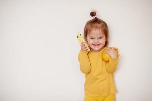 Baby girl in yellow with lemon and mobile phone, isolated background. photo