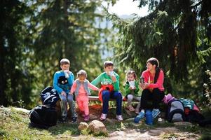 Mother with four kids resting in mountains. Travel and hiking with childrens. Drinking tea in nature. photo