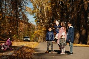 Mother with four kids in autumn park. Family walk in fall forest. photo