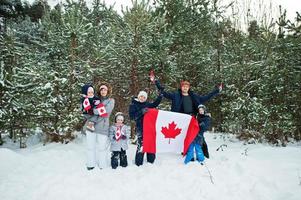 familia sosteniendo la bandera de canadá en el paisaje invernal. foto