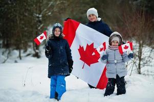 niños sosteniendo la bandera de canadá en el paisaje invernal. foto