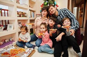 familia feliz con cuatro hijos comiendo pizza en casa. foto