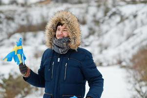 hombre escandinavo con bandera de suecia en el paisaje sueco de invierno. foto