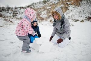 Family plays in winter outdoor, mother and children having fun. photo