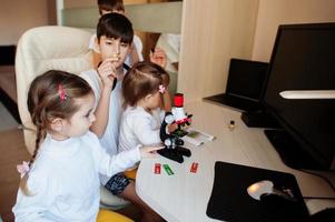 niños usando microscopio aprendiendo clases de ciencias en casa. foto