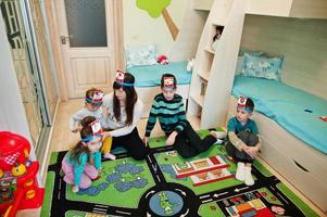 familia feliz con cuatro niños jugando adivina quién mientras se divierte en casa. foto