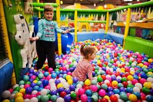 Childrens playing in colorful ball pit. Day care indoor playground. Balls pool for children. Kindergarten or preschool play room.