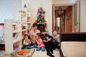 familia feliz con cuatro hijos comiendo pizza en casa. foto