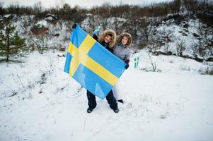 pareja escandinava con bandera de suecia en el paisaje sueco de invierno. foto