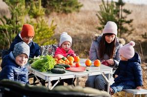 Cheerful mother with kids at a picnic. Family on vacation with fruits outdoor. photo