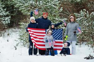 Family with four kids holding flag of USA on winter landscape. photo