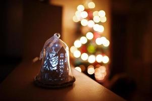 Bell light against Christmas tree with shining garlands on evening home. photo