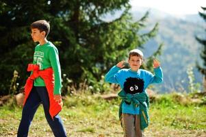 Brothers hike in the mountains, children are walking along a mountain trail, outdoor activities with children, sibling, boy with his brother traveling. photo