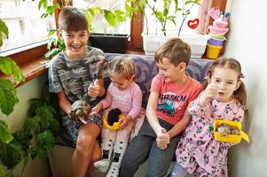cuatro niños con sus mascotas favoritas en las manos. niños jugando con hámster, tortuga en casa. foto