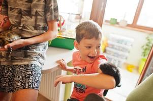 Four children holding their favorite pets on hands. Kids playing with hamster,turtle and parrots at home. photo