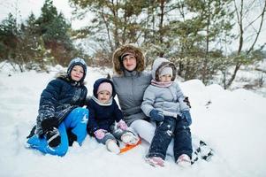 madre con tres hijos en la naturaleza invernal. al aire libre en la nieve. foto
