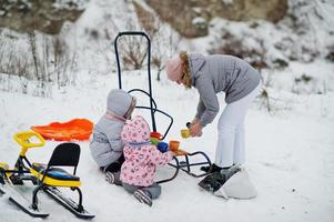 Family plays and sleigh rides in winter outdoor, mother and children having fun, drinking tea. photo