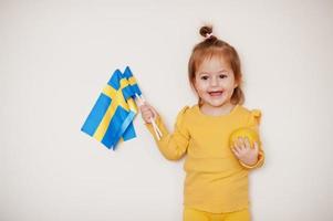 Baby girl in yellow with lemon and Sweden flag, isolated background. photo