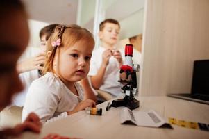 Kids using microscope learning science class at home. photo