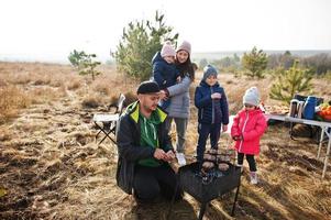 Family barbecuing on a deck in the pine forest. Bbq day with grill. photo