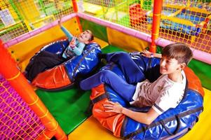 Happy two brothers in tubing donuts enjoying slides in fun children center. photo