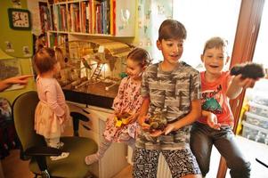 cuatro niños con sus mascotas favoritas en las manos. niños jugando con hámster, tortuga y loros en casa. foto