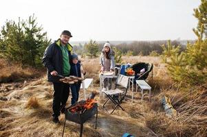 Family barbecuing on a deck in the pine forest. Bbq day with grill. photo