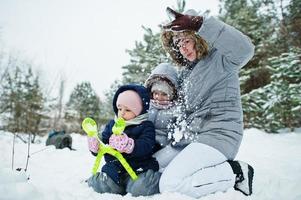 Mother with two baby girl daughters in winter nature. Outdoors in snow. photo