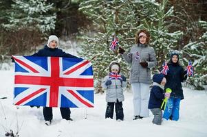 madre con hijos sosteniendo la bandera de gran bretaña en el paisaje invernal. foto