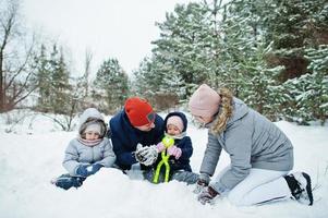 Father and mother with two daughters in winter nature. Outdoors in snow. photo