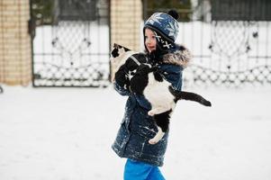 Boy with cat on hands in the yard of house at winter. photo