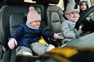 los niños se sientan en un coche eléctrico en el patio de la casa en invierno. foto