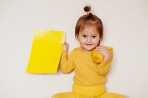 Baby girl in yellow with lemon and card, isolated background. photo