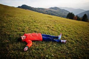 Boy lying in the grass with a gorgeous mountain range in the horizon. photo