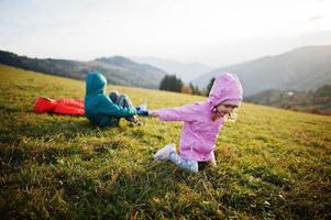 Three kids lying in the grass with a gorgeous mountain range in the horizon. photo