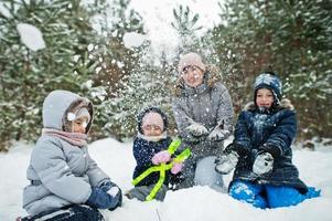 madre con tres hijos en la naturaleza invernal. al aire libre en la nieve. foto