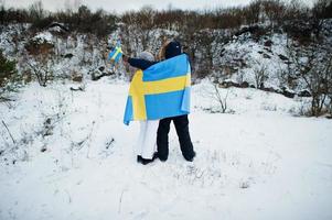 pareja escandinava con bandera de suecia en el paisaje sueco de invierno. foto