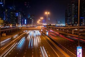 larga exposición de automóviles en movimiento en la carretera nocturna en dubai. vida nocturna en el puerto deportivo de dubai. foto