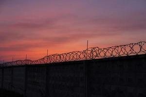silhouette of barbed wire against sunset sky photo