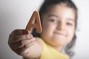 niña sosteniendo una letra del alfabeto esponjosa en la mano derecha foto